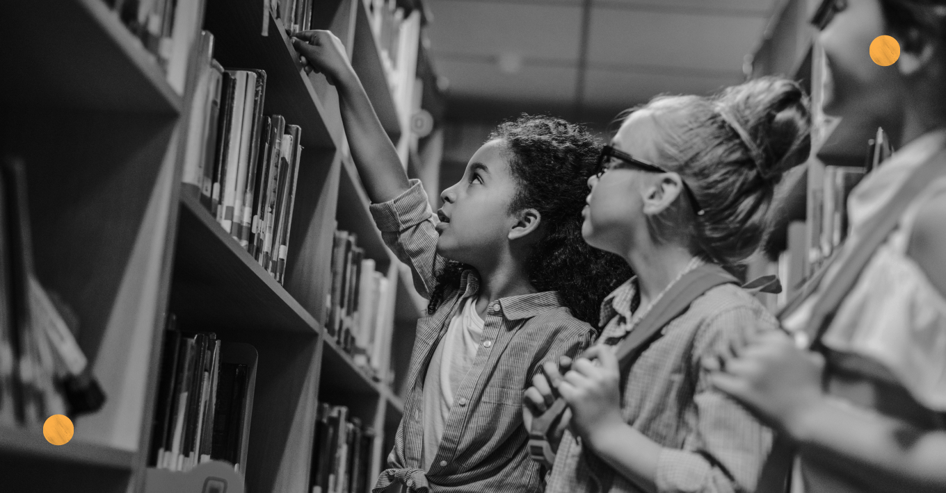 Young students at a library looking at books.
